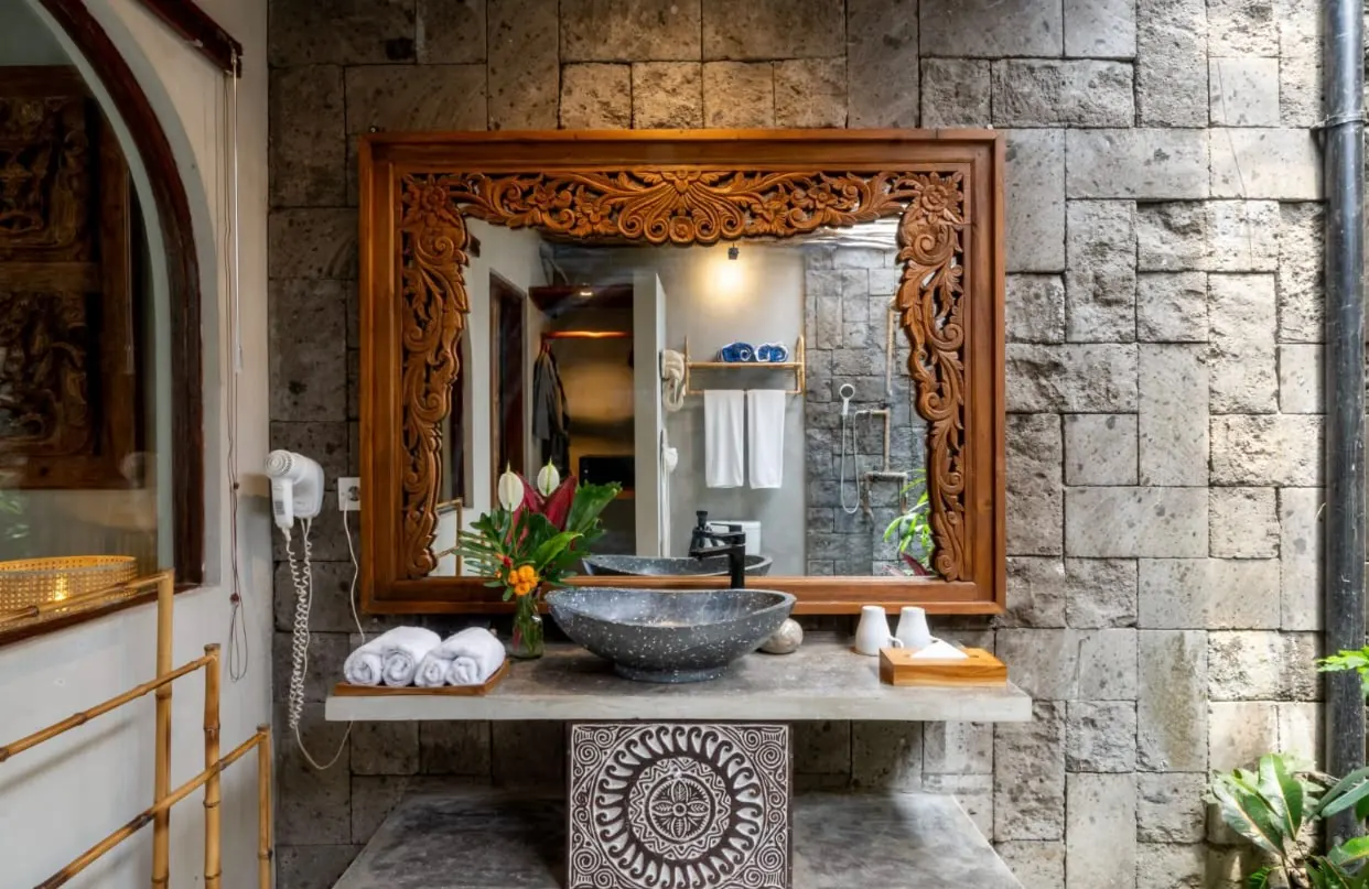 Carved wooden mirror on a natural stone wall