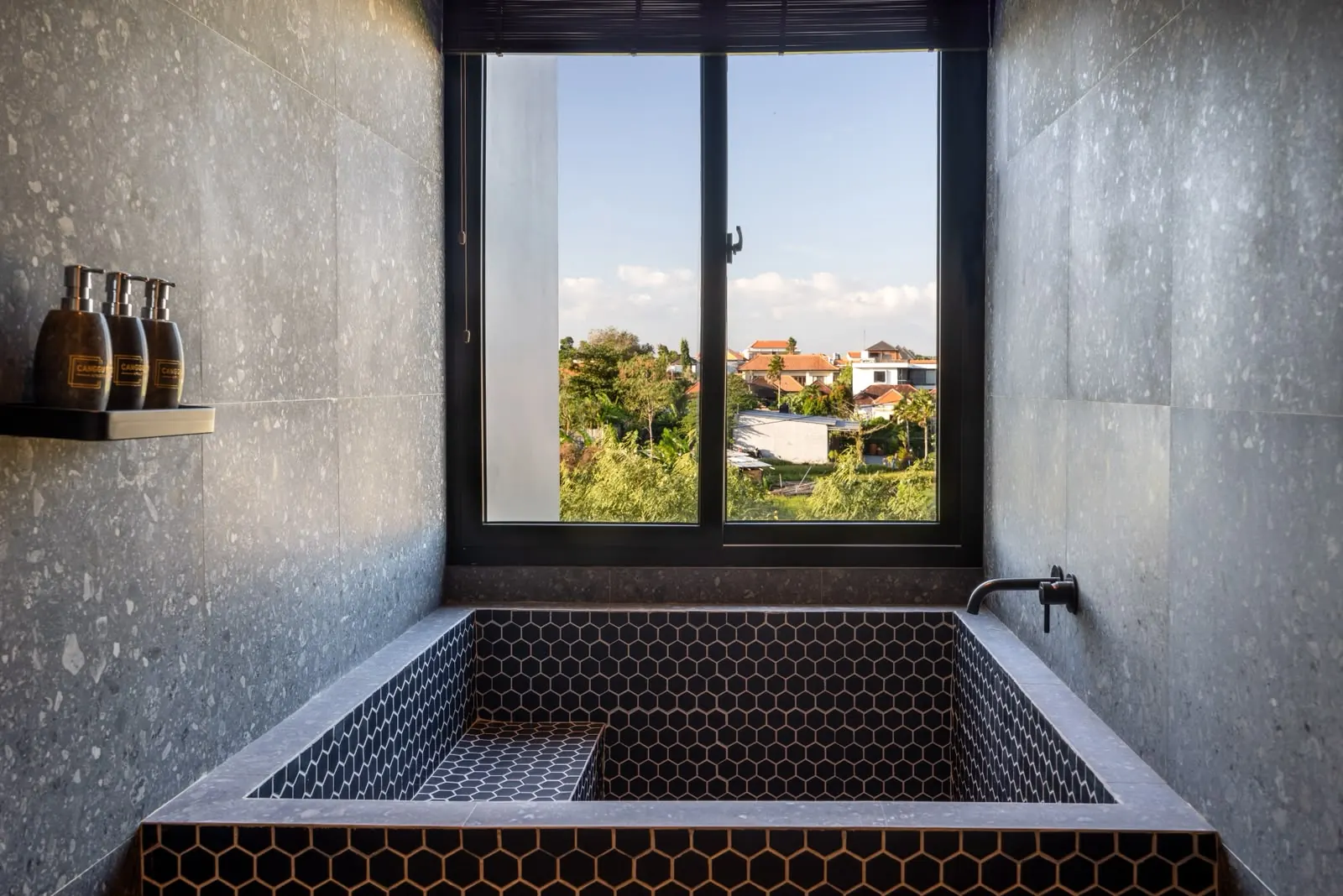Deep tiled soaking tub with treetop view