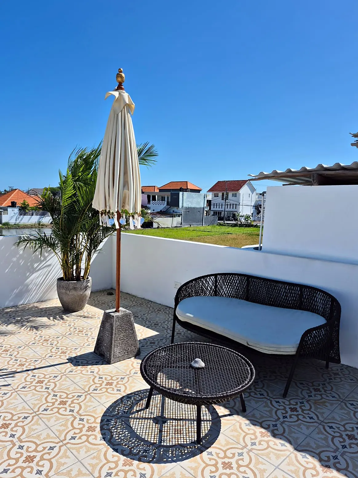 Rooftop terrace with encaustic tiles, rattan loveseat and umbrella