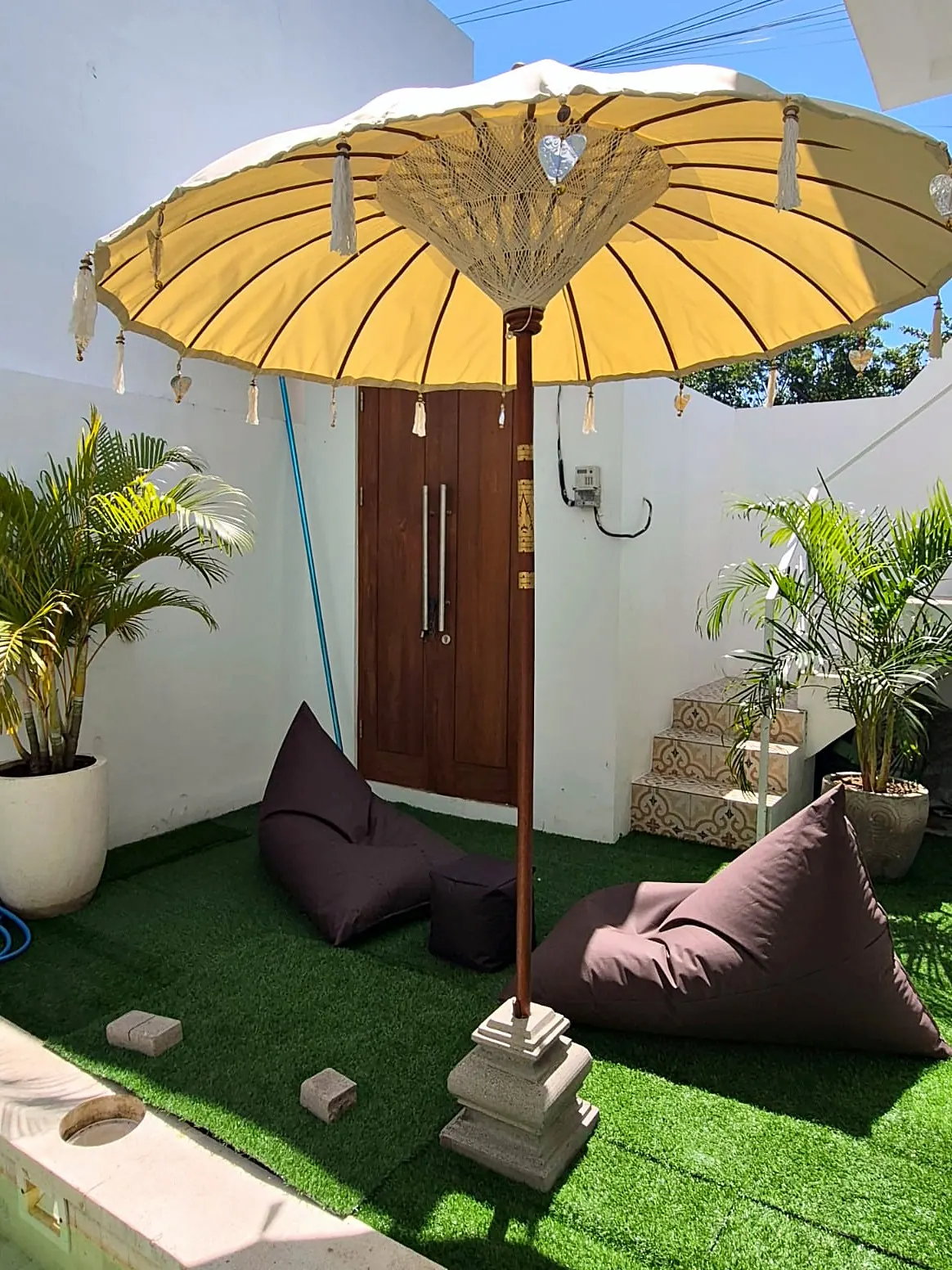 Garden lounge with bean bags and yellow Bali umbrella beside the pool