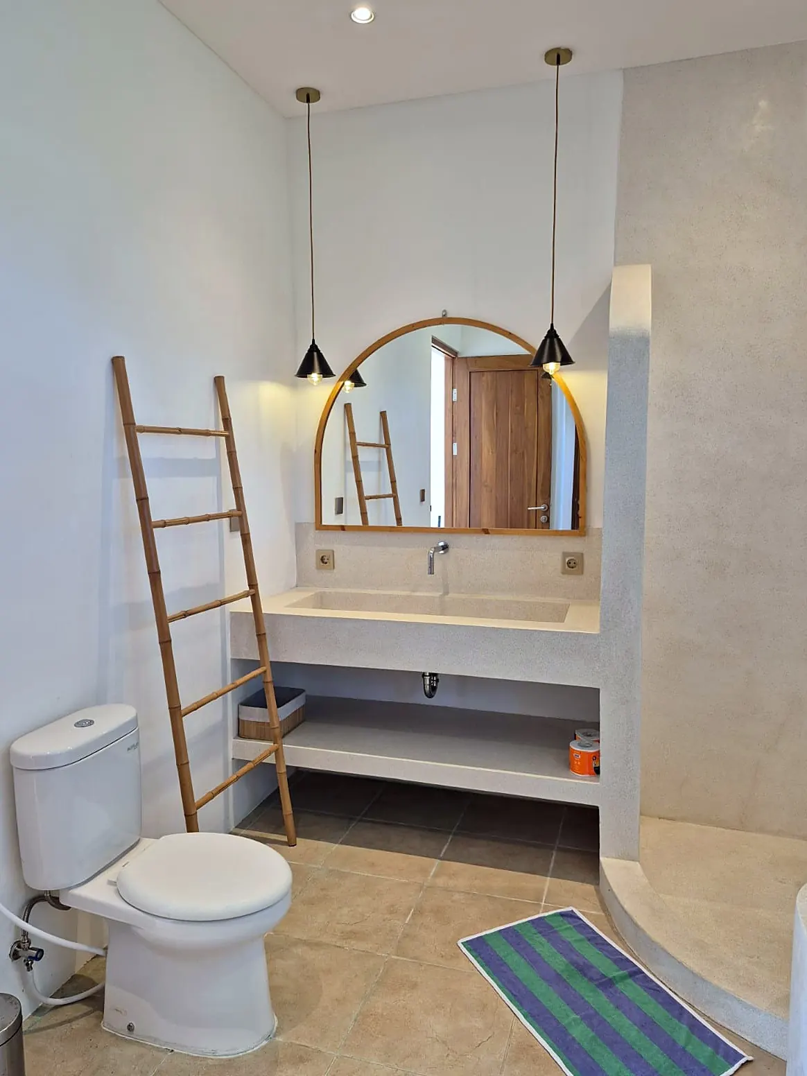 Bathroom with terrazzo sink and arched mirror