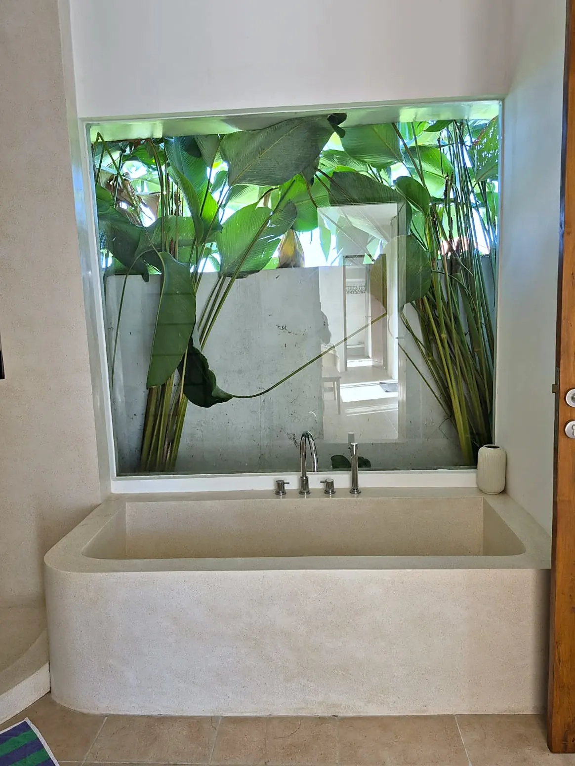 Sunken terrazzo bathtub with a window onto a garden