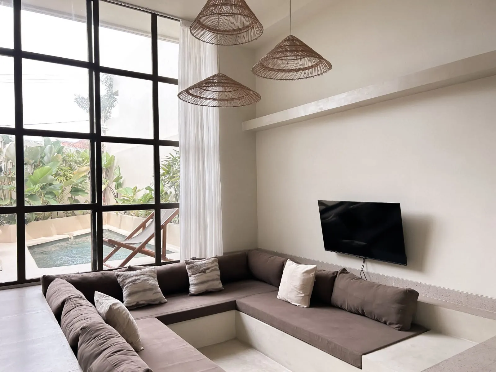 Sunken lounge with double-height black steel windows onto the private pool – 2 bedroom villa for rent in Padonan, Canggu