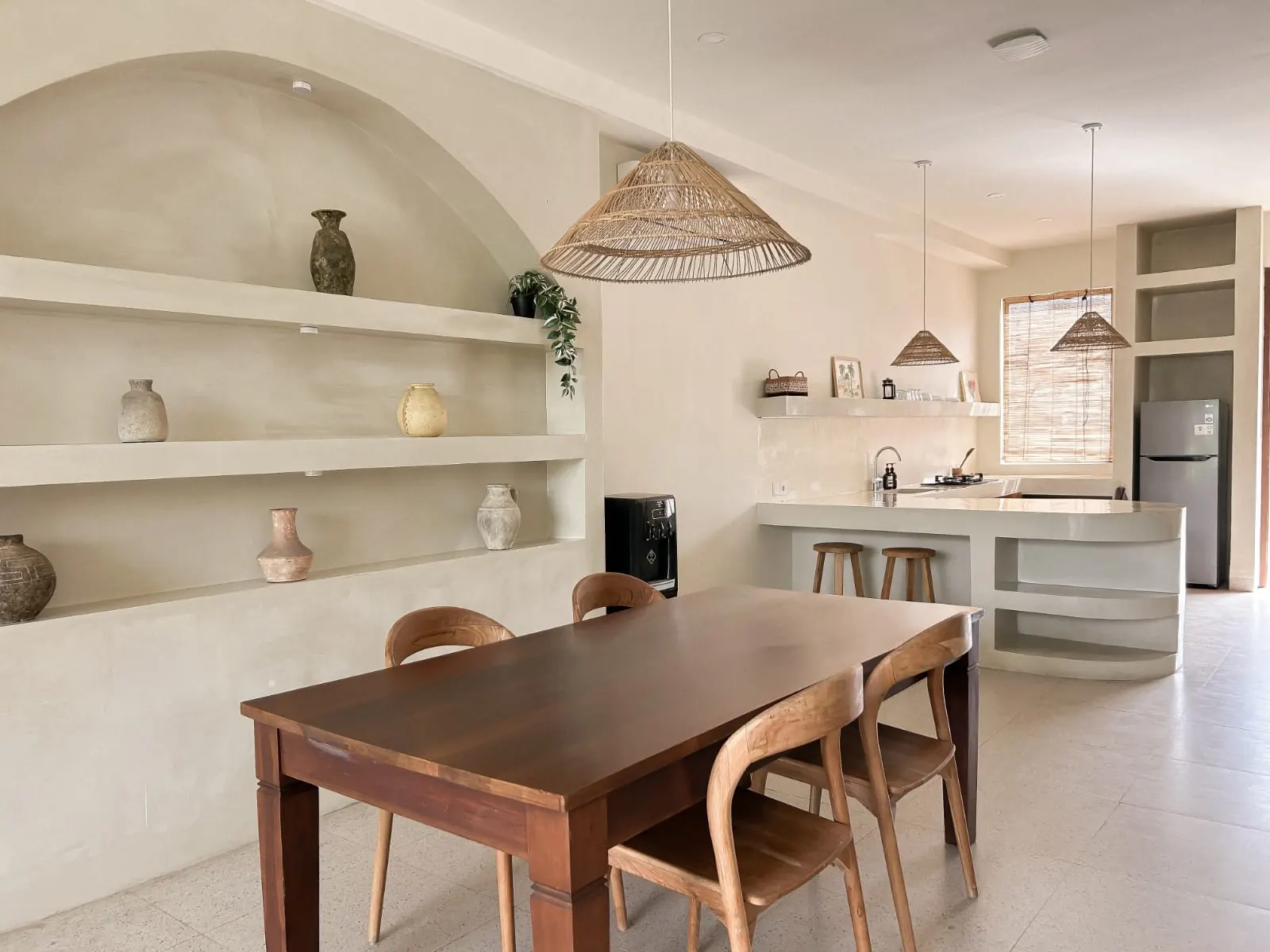Dining table with arched niche shelves and the kitchen beyond