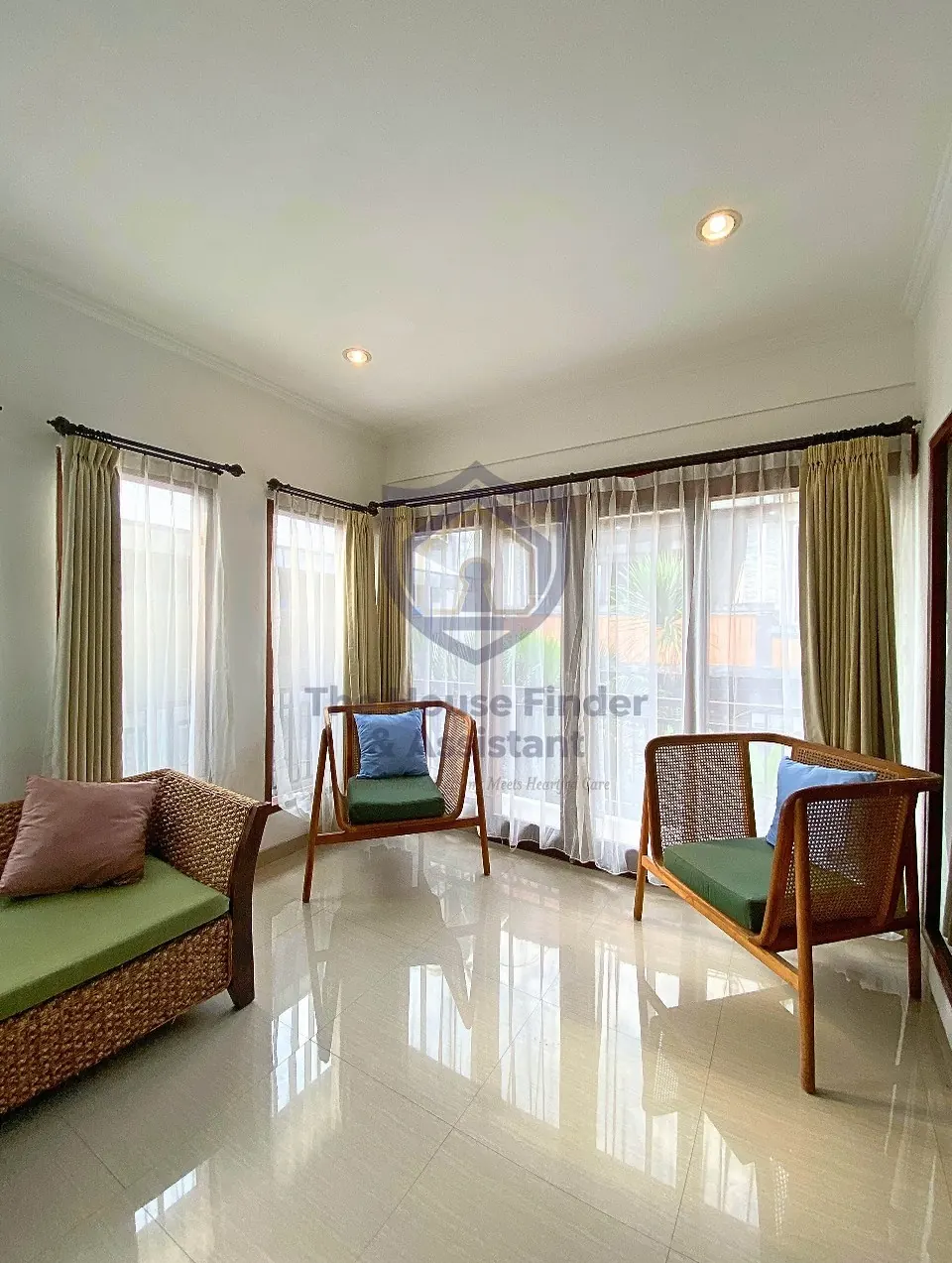 Bright lounge with daybed, armchairs and tall curtained windows